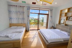 two beds in a room with a large window at Lộc Vừng Homestay in Phan Thiet