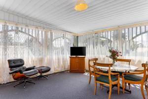 a living room with a table and chairs and a tv at La Maison Boutique Hotel in Katoomba