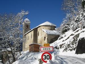 uma estrada coberta de neve com um edifício ao fundo em Gîte Orus em Orus
