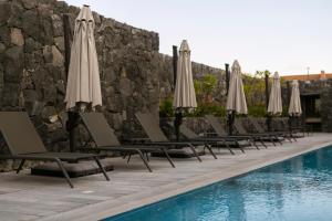 a row of chairs with umbrellas next to a pool at Premium Apartment - Terraza Premium, Pool & Gym in Querétaro