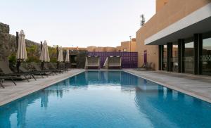 a large swimming pool with chairs and umbrellas at Premium Apartment - Terraza Premium, Pool & Gym in Querétaro