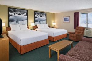 a hotel room with two beds and a chair at Super 8 by Wyndham Antigo in Antigo +15 photos