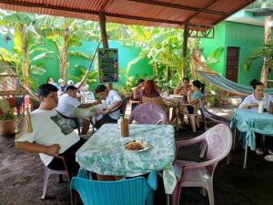a group of people sitting at tables in a restaurant at Cocos Hostel in Moyogalpa +50 photos