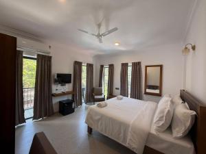 a bedroom with a white bed with a ceiling fan at Henmil Hideaway in Anjuna