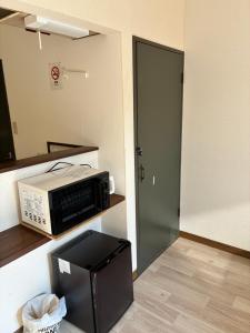 a microwave sitting on a shelf next to a door at アルピエh 108号室WiFi使えます in Hanabatachō +10 photos