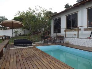 a house with a swimming pool and an umbrella at WSL Saqua, Suite com ar, piscina, lounge, salão festas, churrasqueira, jogos, jardim, estacionamento 800m2 in Saquarema