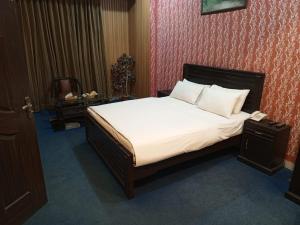 a bedroom with a large bed with white sheets and pillows at Divine Hotel1 in Islamabad