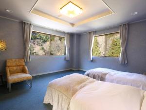 a bedroom with two beds and a chair and windows at Shoji Mount Hotel in Fujikawaguchiko