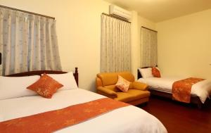 a hotel room with two beds and a chair at 宜蘭樂活小屋 in Dongshan