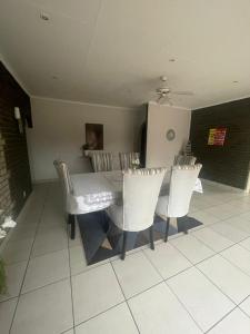 a dining room with a table and white chairs at 33 Boeren Guesthouse in Vryheid