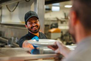 a man is holding a plate in a kitchen at The Lodge Village - Workforce Accommodation in Moranbah