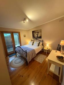 a bedroom with a bed and a table with lamps at The Green Room Wattle Glen in Wattleglen