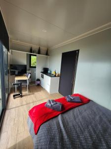 a bedroom with a red blanket on top of a bed at Gore Bay View, Tiny Pod, Treehouse in Gore Bay +3 photos