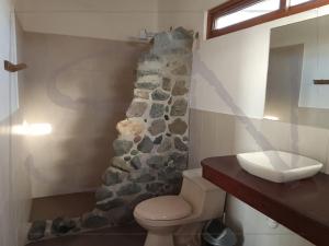 a bathroom with a stone wall next to a toilet at Seaside Nord in Máncora