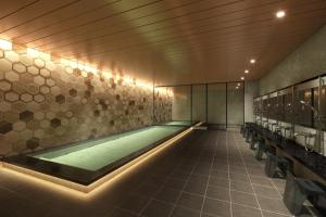 a swimming pool in a bathroom with lights on the wall at Via Inn Prime Kumamoto in Kumamoto