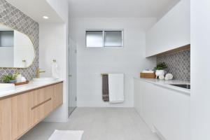 a white bathroom with a sink and a mirror at Tilligerry Beach Retreat in Taylors Beach +33 photos