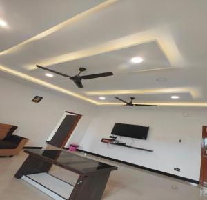 a living room with a ceiling fan and a tv at The Canalway Inn in Pollāchi +42 photos