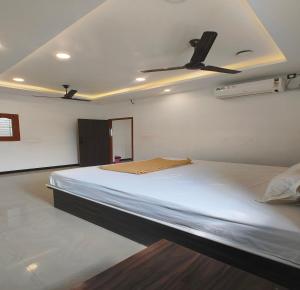 a bedroom with a large bed with a ceiling fan at The Canalway Inn in Pollāchi