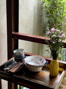 a table with two bowls and a vase with flowers at Cat Bungalow Stay in Cư Chinh +32 photos
