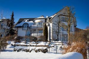 a large white house with snow on the ground at Villa Katharina Ferienwohnungen in Willingen