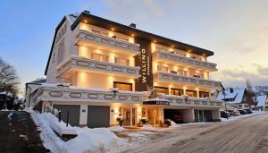 a large building on a snow covered street at WILLINO Privathotel in Willingen