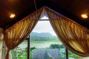a window with curtains and a view of a river at Hill Paradise Nuwaraeliya in Nuwara Eliya