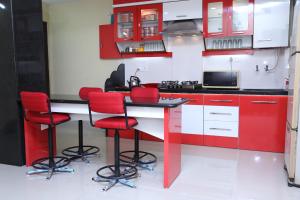 那格浦爾的住宿－Shivam Apartment，厨房配有红色和白色的橱柜和红色凳子