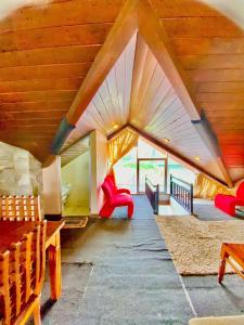 a living room with wooden ceilings and red chairs at Hill Paradise Nuwaraeliya in Nuwara Eliya