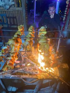 a man is cooking food on a grill at Hotel Tiger's Den - Peace Home, Family -an exciting adventurous park safari, arranger in Sauraha