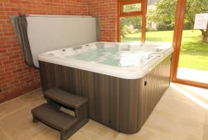 a hot tub with a chair next to a window at Montgomery Barn in Bideford