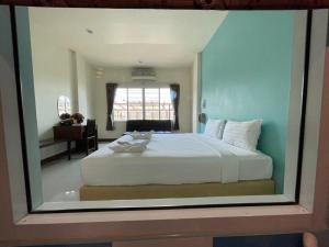 a bedroom with a large white bed with a window at โรงแรมพันวลี in Ban Hua Phrong