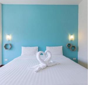 two white swans forming a heart on a bed at โรงแรมพันวลี in Ban Hua Phrong