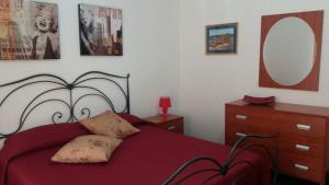 sypialnia z czerwonym łóżkiem z lustrem i komodą w obiekcie Case vacanze Alice e Salvo w mieście Avola