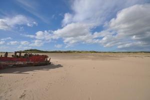 an old boat sitting on the sand on a beach at Montgomery Barn in Bideford