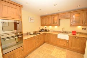 a kitchen with wooden cabinets and stainless steel appliances at Montgomery Barn in Bideford