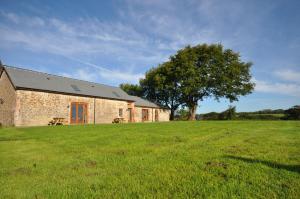 a brick building with a tree in the middle of a field at Montgomery Barn in Bideford