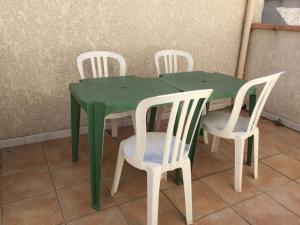 a green table with four white chairs around it at Appartement Village Le Liberty 1 Argelès Sur Mer 2km plage in Argelès-sur-Mer