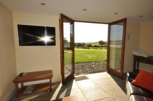 een kamer met een glazen schuifdeur met uitzicht op een veld bij Montgomery Barn in Bideford