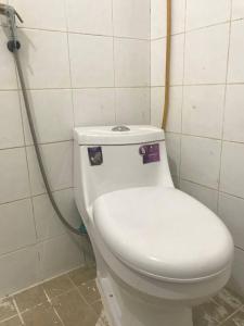 a white toilet in a bathroom with a hose at The Panda Backpacker Hostel in Kampot