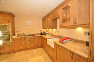 a kitchen with wooden cabinets and a sink at Montgomery Barn in Bideford