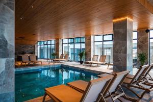 a lobby with a pool with chairs and windows at Sim Seaside Odyssey in Mamaia Sat/Năvodari