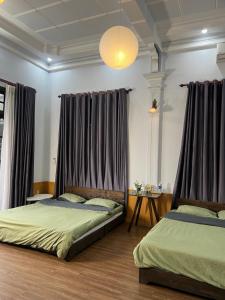 two beds in a bedroom with curtains and a table at Susu Homestay Hue in Thôn Kim Long (1)