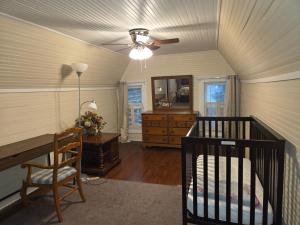 a room with a crib and a ceiling fan at Brick House Retreat in Hamlet