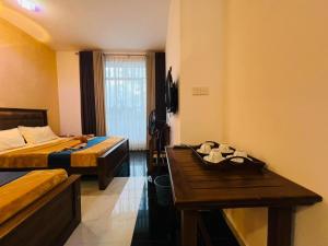 a hotel room with two beds and a wooden table at Adams Peak Lake Resort in Nallathanniya