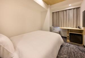 a hotel room with a white bed and a desk at Via Inn Prime Kumamoto in Kumamoto