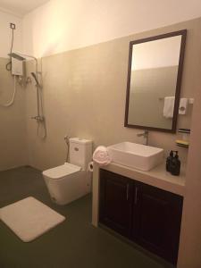 a bathroom with a toilet and a sink and a mirror at The Arch View in Habaraduwa Central