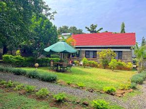 a house with a table and an umbrella in the yard at Spacious Homely ap 5BR in Kisumu