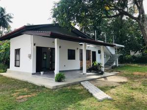 a small white house with a porch at The Vinza in Hikkaduwa +6 photos