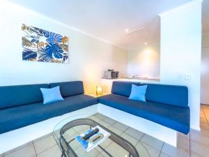 a living room with a blue couch and a table at Mango Palms in Airlie Beach