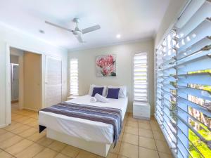 a bedroom with a bed and a wall with windows at Mango Palms in Airlie Beach